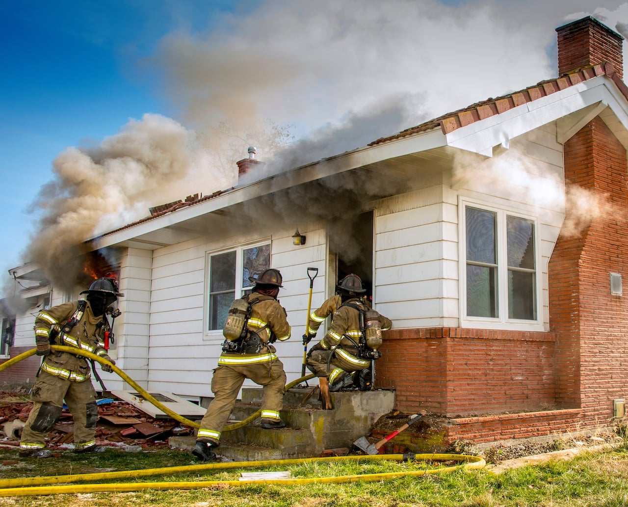 Firefighters entering a burning home
